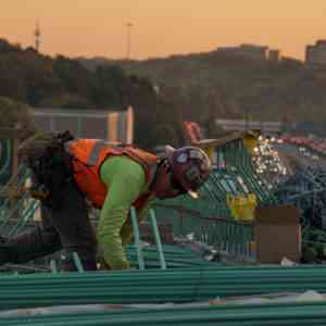 Man working on top of a building being built. Alliance United workplace safety services in New England.
